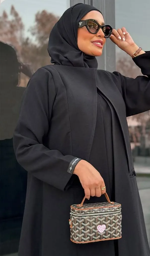 Model in an open-front black abaya adjusting her sunglasses