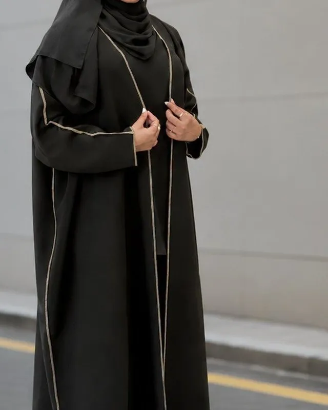 Front edge and cuffs of the black abaya showing the gold-tone piping