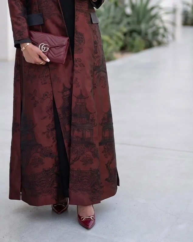 Lower half of the burgundy brocade abaya showing the black pictorial pattern